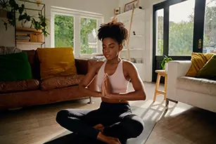 African-American woman meditating, doing yoga in living room