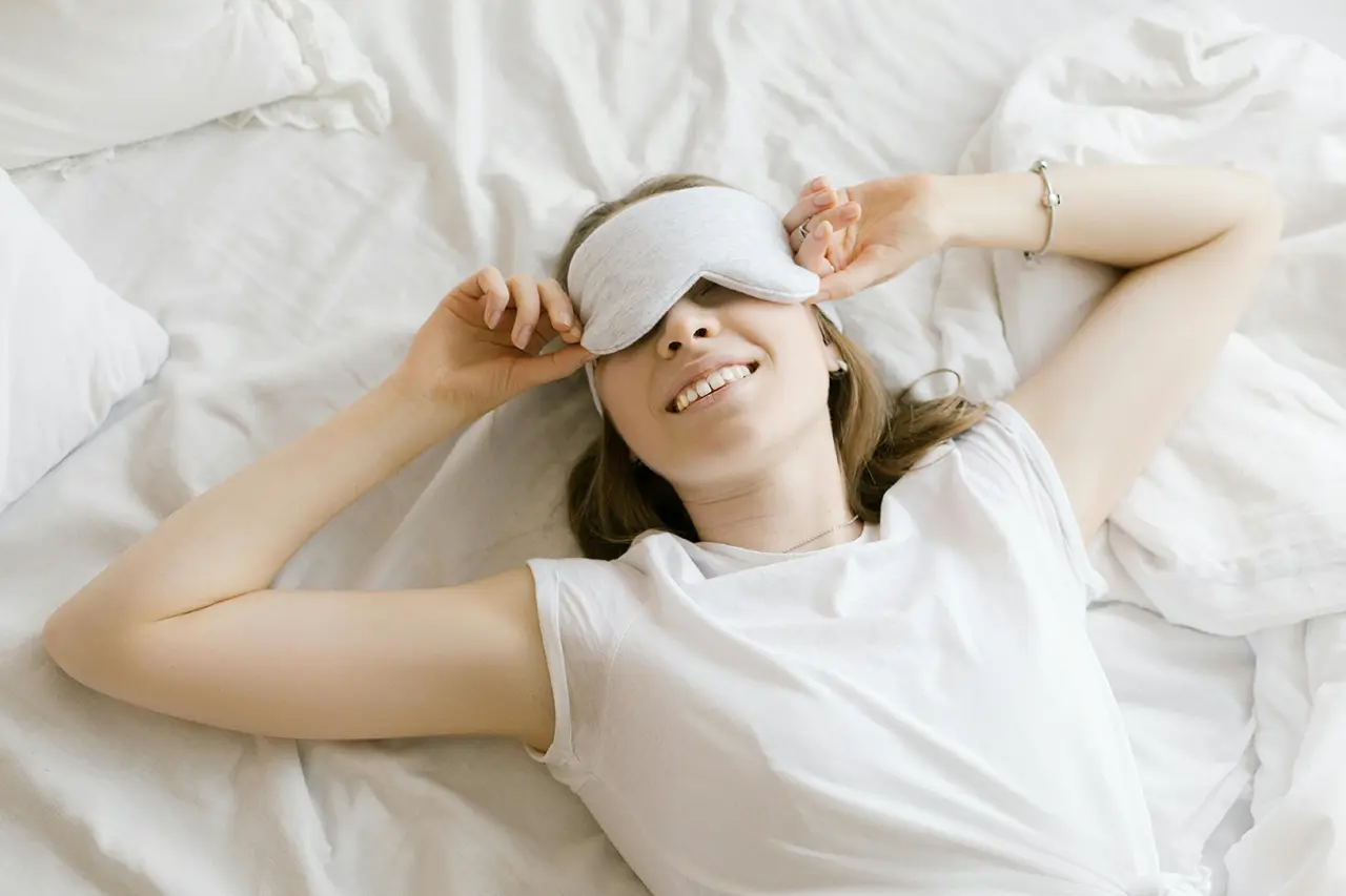 woman with sleep mask laying in bed